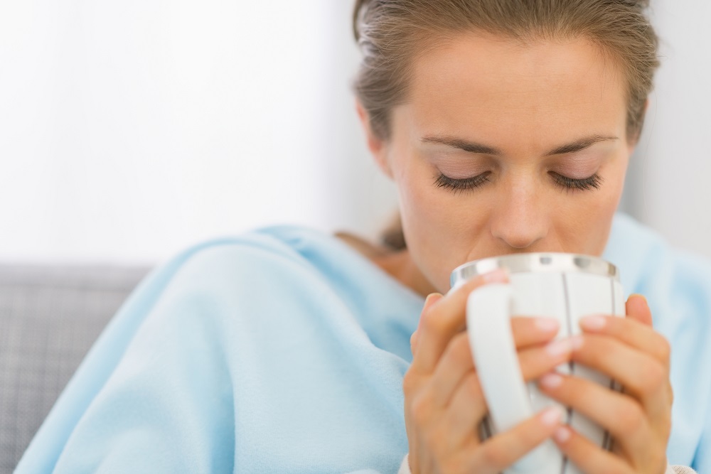 Ill young woman drinking hot beverage