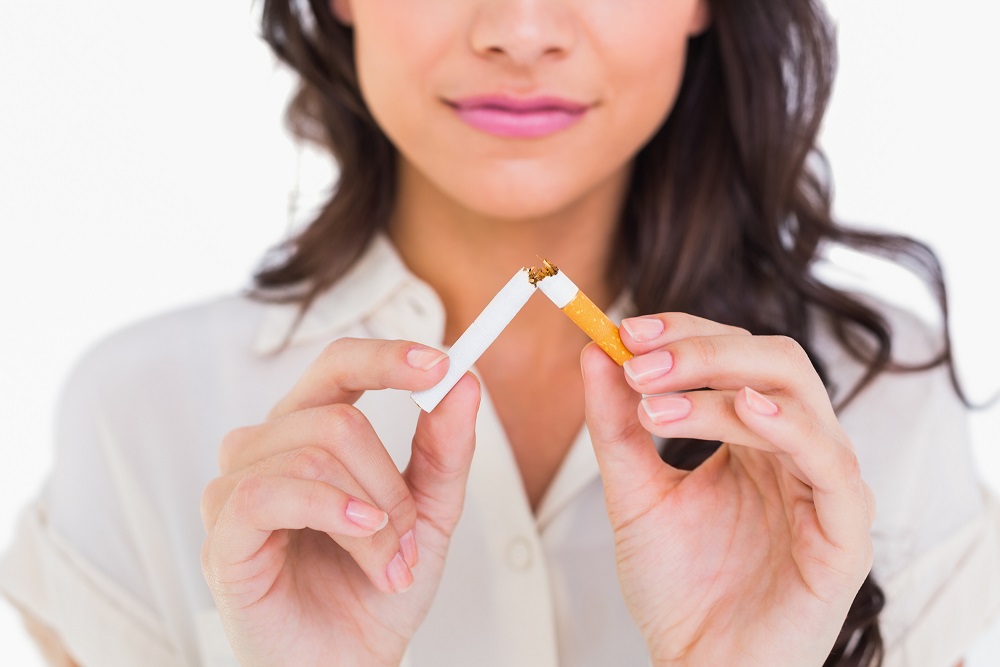 Brunette snapping her cigarette on white background